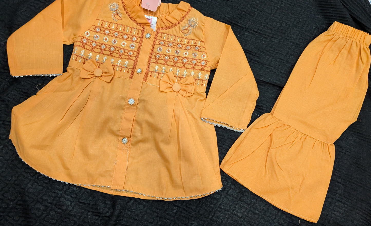 Infant peach-orange peplum outfit a high neckline, crystal buttons, geometric embroidery, and matching flounced garara pants.